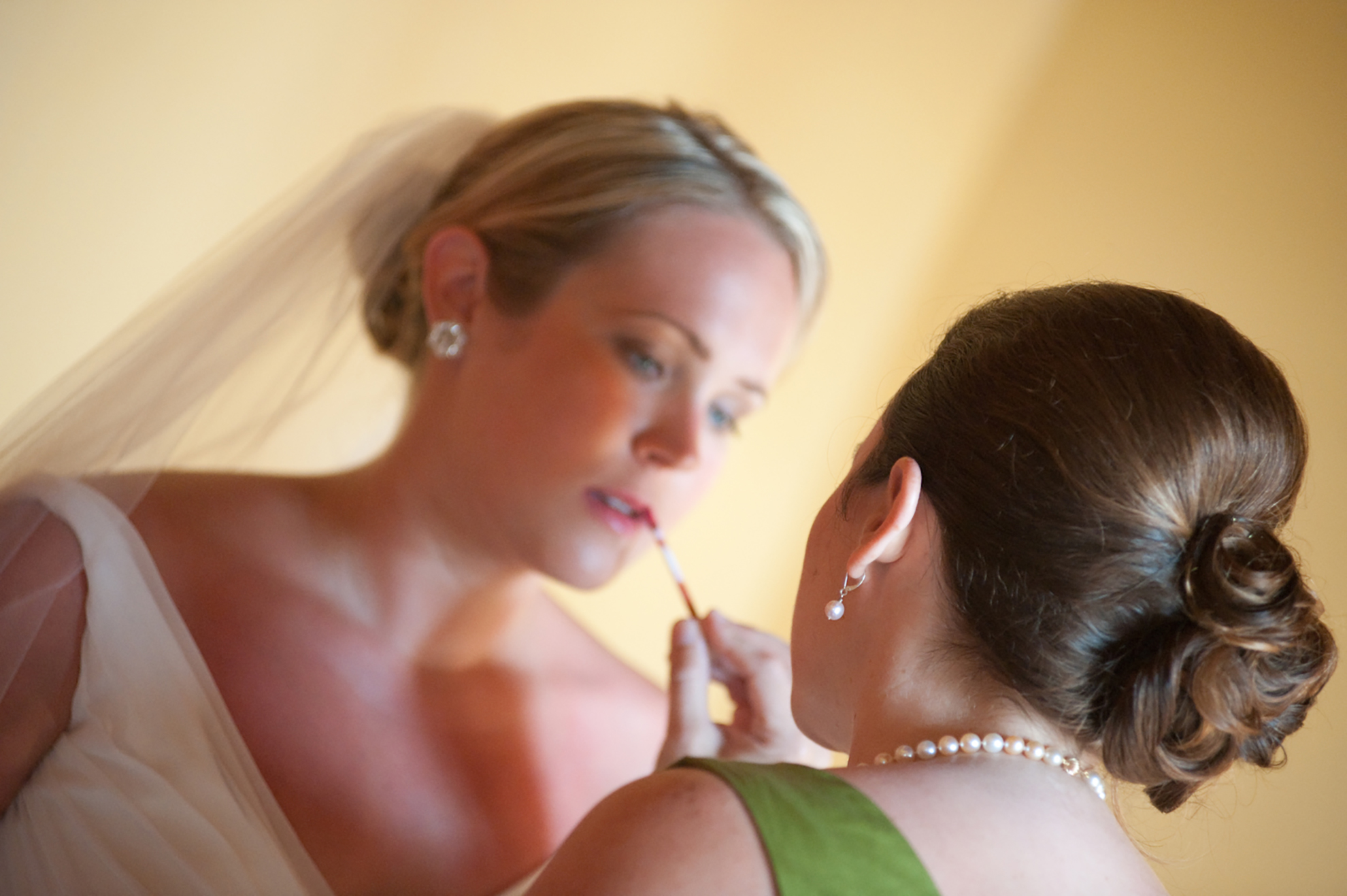 bride getting her makeup done in her dress and veil