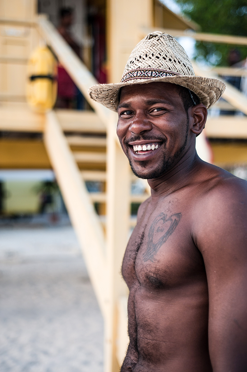 shirtless man smiling with wicker hat on