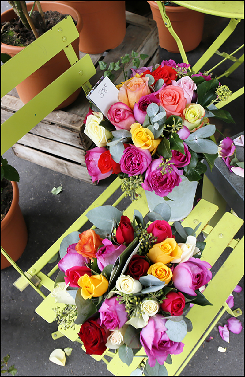 Two brightly colored bouquets of various flowers sitting on a yellow-green metal slotted chair