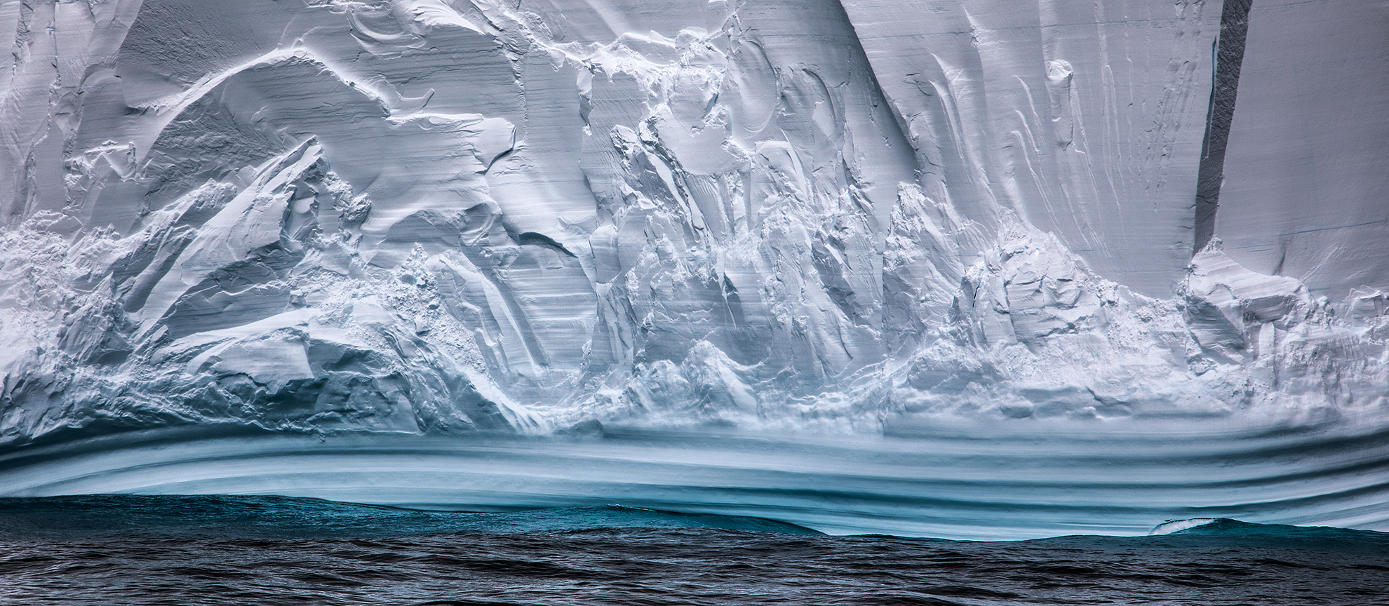 Zoomed in photo of the bottom of an iceberg showcasing the patterns created by the waves