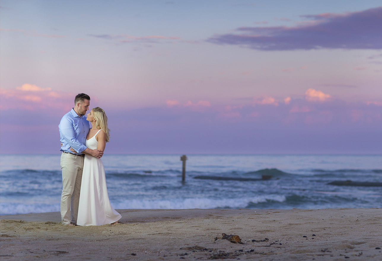 Image of a couple on the beach holding each other with the waves in the background