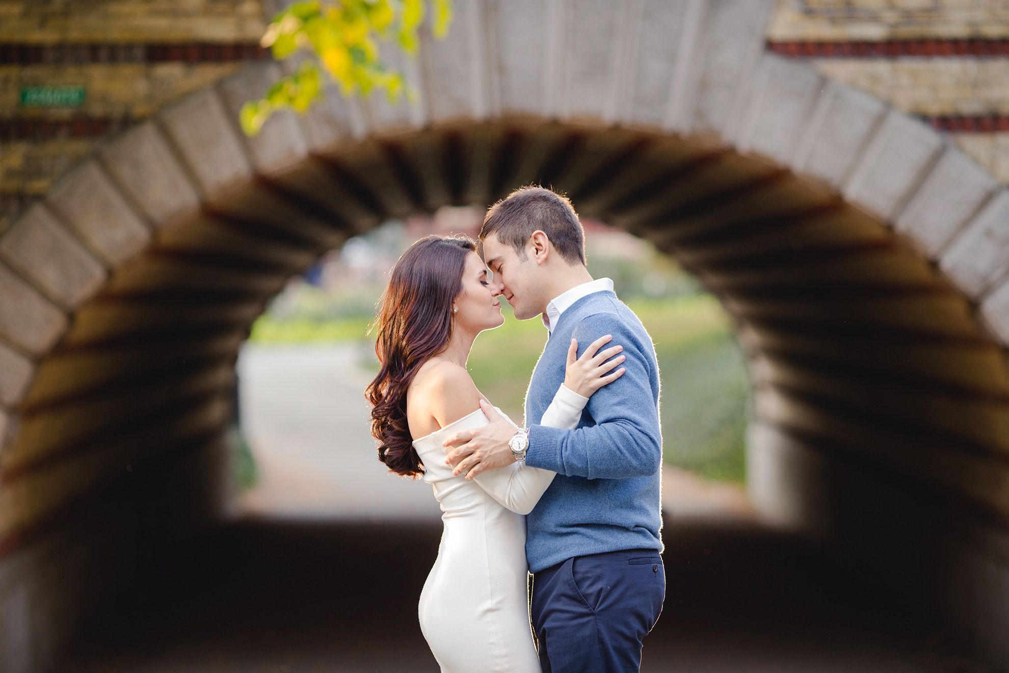 Image of an engaged couple embracing in front of a stone tunnel