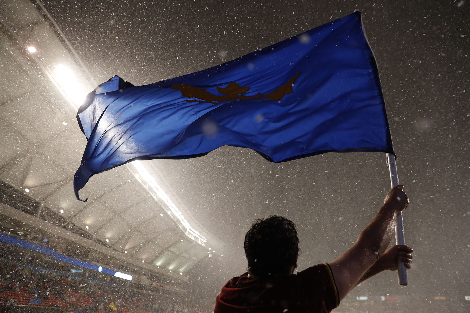Soccer action shot - player waving a large blue flag as it snows in the stadium
