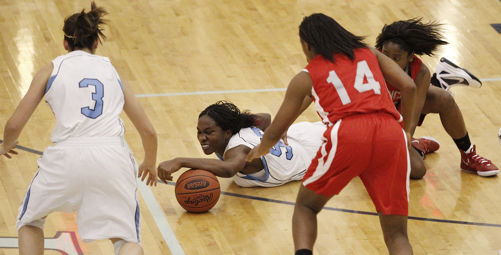 Women's Basketball action shot - one woman diving for the ball on the ground while others swarm around her