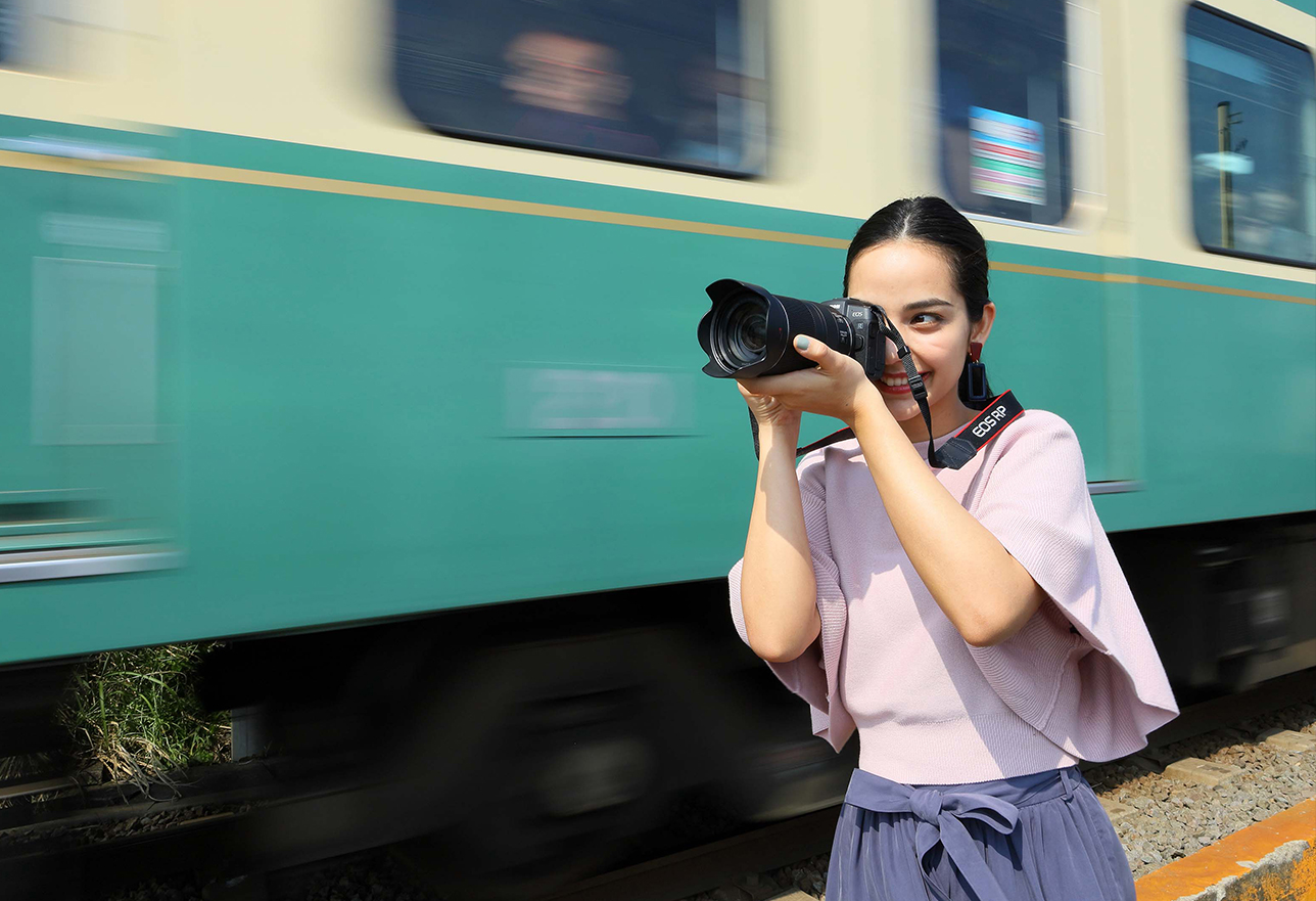 Woman using camera, standing next to train