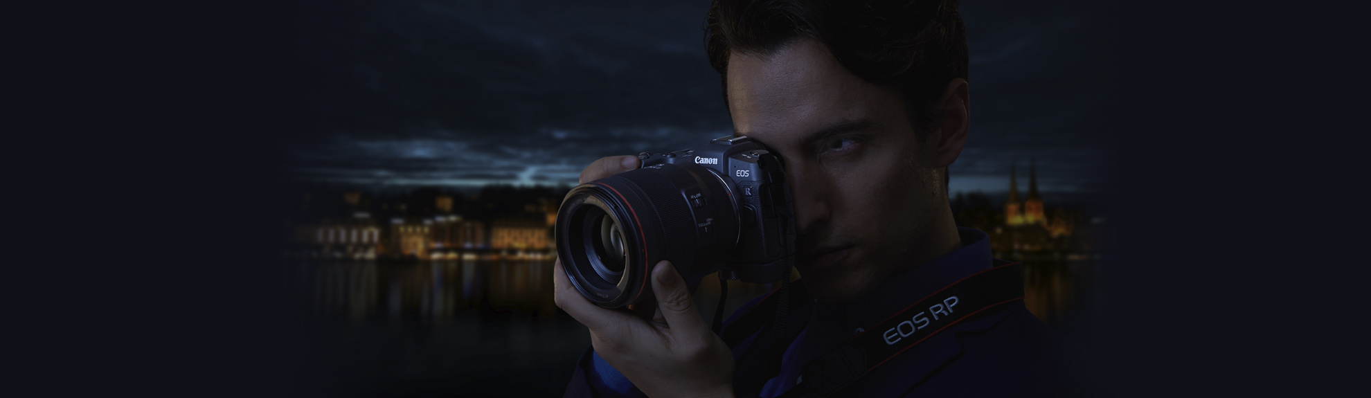 Photographer looking through the Canon RP's viewfinder with a dark background